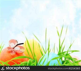 Easter colorful eggs border with fresh green grass over natural blue sky background, traditional christian decoration for a spring holiday, card design of festive food
