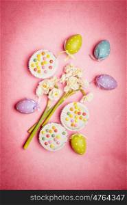 Easter composing with spring flowers, egg and cakes on pink background, top view
