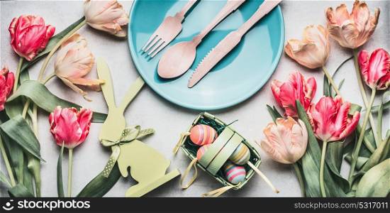 Easter composing with spring tulips , bunny decor, eggs and festive table setting with plate and cutlery, top view, banner