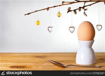 Easter composition with egg and catkins on wooden background. Egg painted a beige paint