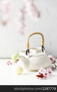 Easter composition with White ceramic teapot, Easter eggs and spring flowers on white table