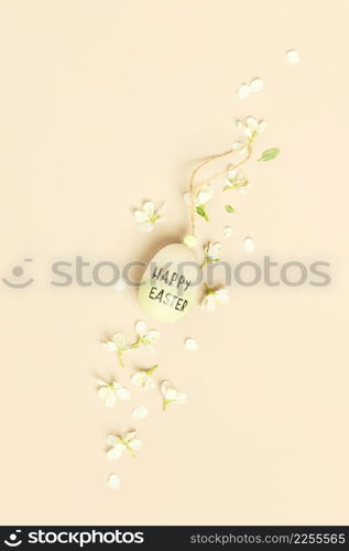 Easter composition with wooden easter egg on beige background with flowers, flat lay. Happy easter concept