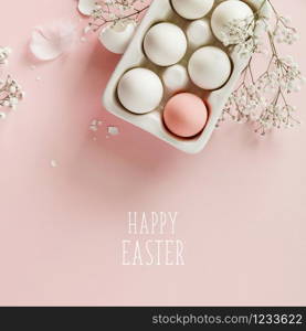 Easter concept. Eggs in white ceramic holder and flowers on pink background, flat lay, copy space. Easter eggs in white ceramic holder and flowers on pink background