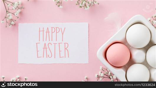 Easter concept. Eggs in white ceramic holder and flowers on pink background, flat lay, copy space