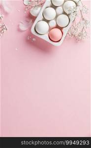 Easter concept. Eggs in white ceramic holder and flowers on pink background, flat lay, copy space