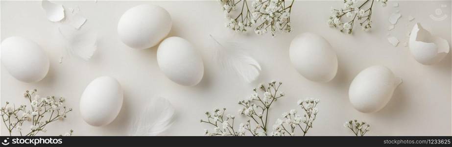 Easter concept. Eggs, petals, feather and flowers on white background, flat lay, top view