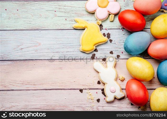 Easter cookies and colorful eggs on pink wooden background with copy space. Easter breakfast on pink wooden background