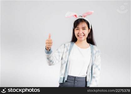 Easter day concept. Smiling happy woman wearing rabbit ears show thumb up for good sign, studio shot isolated on white background with copy space