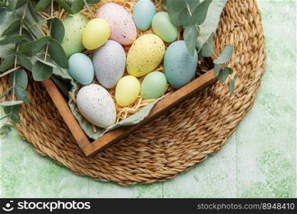 Easter decor. Colored Easter eggs in a wooden box on the table. The concept of preparing for the celebration.