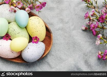 Easter decor. Colored Easter eggs on a wooden plate on the table. The concept of preparing for the celebration.