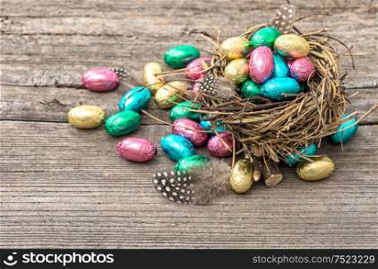 Easter decoration. Colorful chocolate eggs on wooden background.