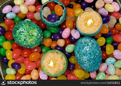 Easter decoration - colorful dyed eggshell candles on a background of candy.