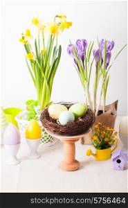 Easter decorations - egg candles, nest and flowers on the table