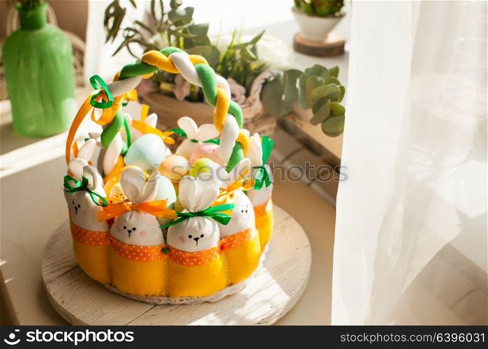Easter decorations - textile basket with rabbits and eggs, morning light from window. Easter textile basket