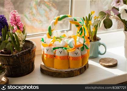 Easter decorations - textile basket with rabbits and eggs, morning light from window. Easter textile basket