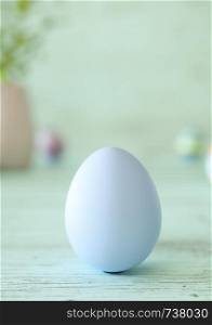 Easter egg standing on its blunt end, decorated in blue. Close-up view with blurred cyan background with copy space