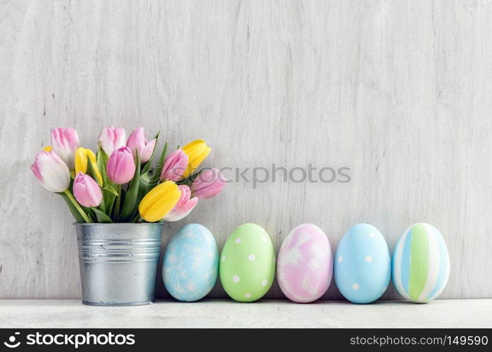 Easter eggs and a spring bouquet of tulips on a wooden table. Springtime decoration.. Easter eggs and a spring bouquet of tulips on a wooden table.