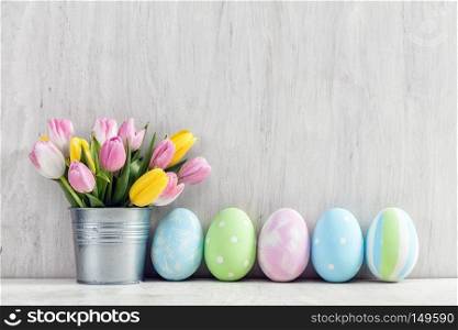 Easter eggs and a spring bouquet of tulips on a wooden table. Springtime decoration.. Easter eggs and a spring bouquet of tulips on a wooden table.