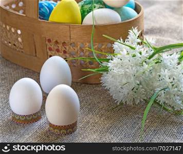 Easter eggs and basket with dyed eggs, a bouquet of white flowers