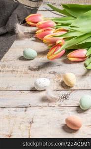 Easter eggs and blossom tulips on background. Top view flat lay.Bright pink and yellow tulip spring flower . Easter composition with colorful Easter eggs and spring flowers tulips on wooden background. Easter card copy space.
