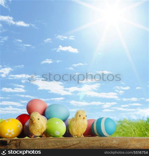 Easter eggs and chickens on green grass and sky background