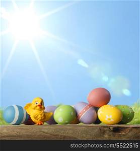 Easter eggs and chickens on green grass and sky background