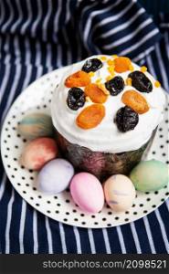 Easter eggs and Easter cake lie on a plate lying on a striped blue apron. Easter religious holiday concept. Easter eggs and Easter cake lie on a plate lying on a striped blue apron. Easter religious holiday concept.