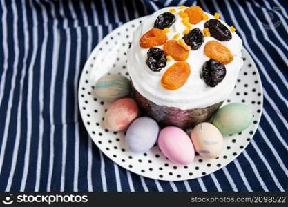 Easter eggs and Easter cake lie on a plate lying on a striped blue apron. Easter religious holiday concept. Easter eggs and Easter cake lie on a plate lying on a striped blue apron. Easter religious holiday concept.