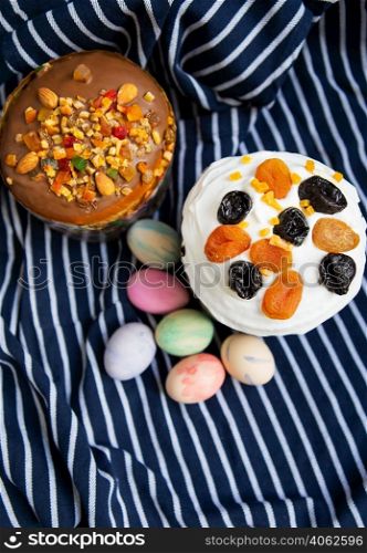 Easter eggs and Easter cakes lie on a striped blue apron. Easter religious holiday concept. Easter eggs and Easter cakes lie on a striped blue apron. Easter religious holiday concept.