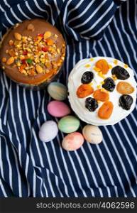 Easter eggs and Easter cakes lie on a striped blue apron. Easter religious holiday concept. Easter eggs and Easter cakes lie on a striped blue apron. Easter religious holiday concept.