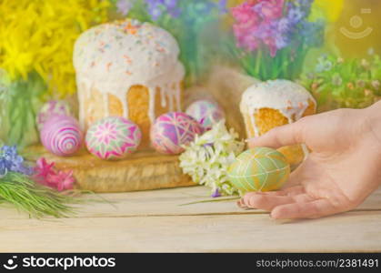 Easter eggs and Easter decoration on the wooden background. Hands holding painted Easter egg. Colorful easter eggs in female hand.. Female hand with Easter eggs. Table decorating for Easter holiday.