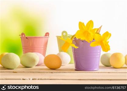 Easter eggs and flowerpots with daffodils on a wooden table