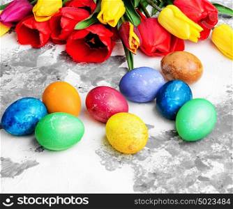 Easter eggs and tulips. Bright Easter colored eggs and bunch of spring tulips