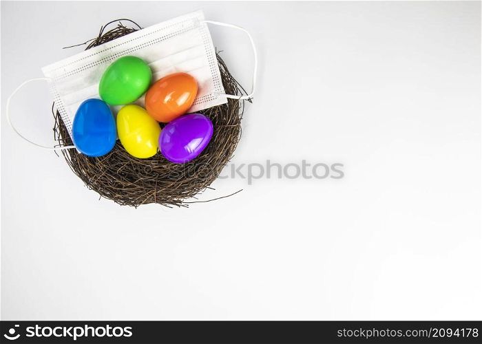 Easter eggs colorful painted in bird nest with protective Face mask top view, Happy Easter Holiday,medical health, Covid-19, coronavirus concept copy space white background. Easter eggs colorful painted in bird nest with protective Face mask top view, Happy Easter Holiday,medical health, Covid-19, coronavirus concept copy space isolated on white background