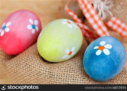 Easter eggs decorated with daisies and a sack on a wooden background