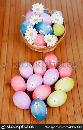 Easter eggs decorated with daisies tucked in a basket on a wooden background