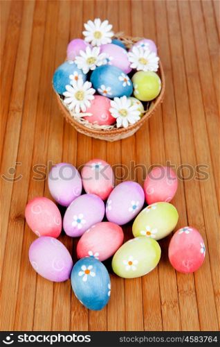 Easter eggs decorated with daisies tucked in a basket on a wooden background