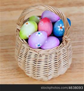Easter eggs decorated with daisies tucked in a basket on a wooden background