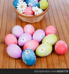 Easter eggs decorated with daisies tucked in a basket on a wooden background