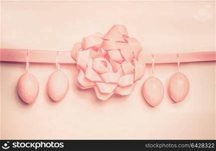 Easter eggs hanging on pink ribbon with bow , pastel color