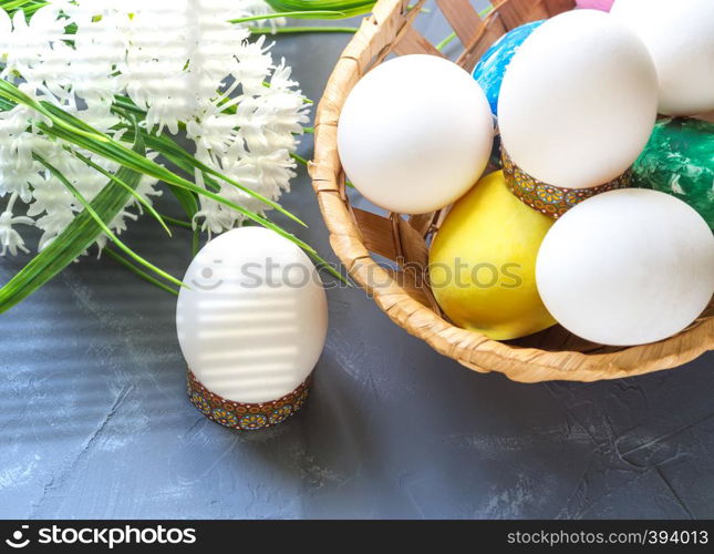 Easter eggs in a basket and white flowers in a dark blue background