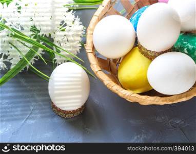 Easter eggs in a basket and white flowers in a dark blue background