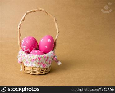 Easter eggs in a basket weave wood on the right corner on a brown background. Pink easter eggs with brown background. Eggs was coloring in the festival of Easter.