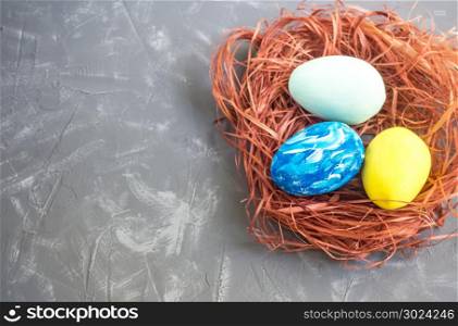 Easter eggs in a nest and white flowers on a gray background