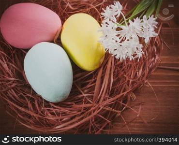 Easter eggs in a nest and white flowers on a wooden background