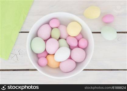 Easter eggs in a white bowl on a wooden table