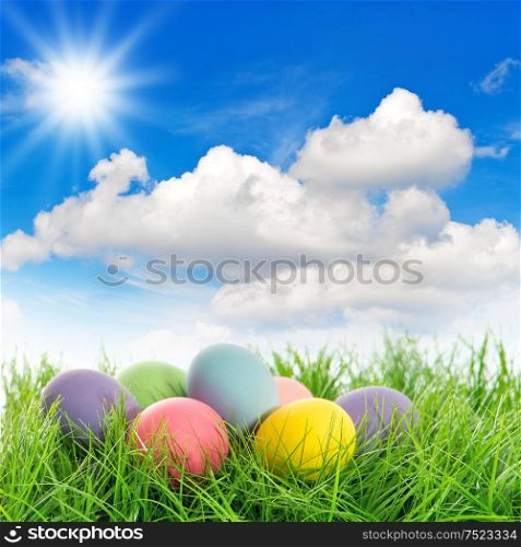 Easter eggs in green grass. Sunny blue sky. Spring landscape