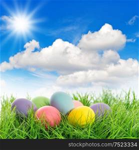 Easter eggs in green grass. Sunny blue sky. Spring landscape