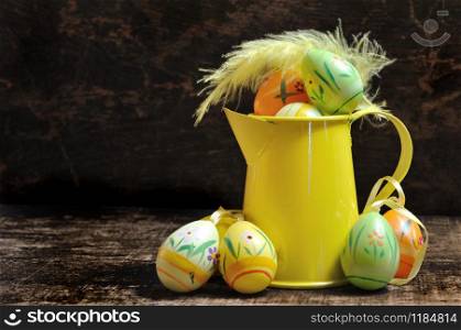 Easter eggs in little watering can on dark wooden background