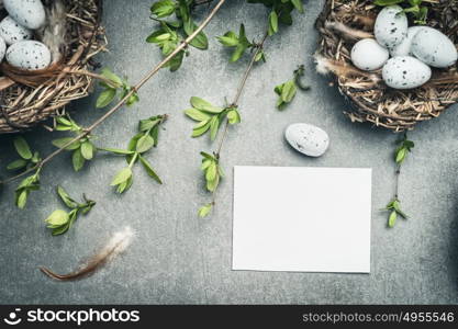 Easter eggs nest with bird feathers and blank white paper card, top view